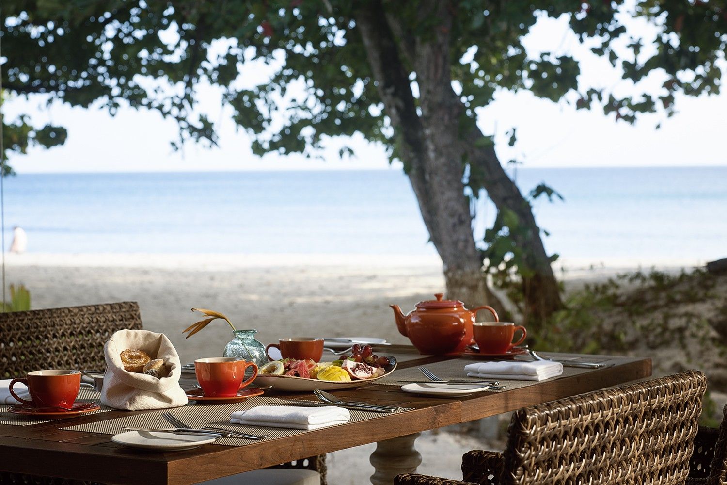 A table set for a meal with a view of the beach and ocean.