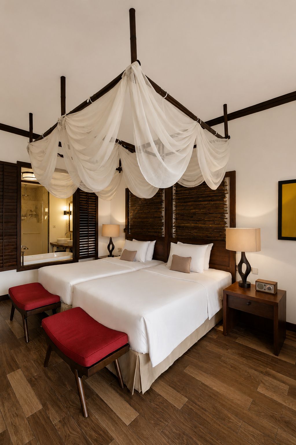 A hotel room with a large bed, two bedside tables, a red bench, and a canopy bed.