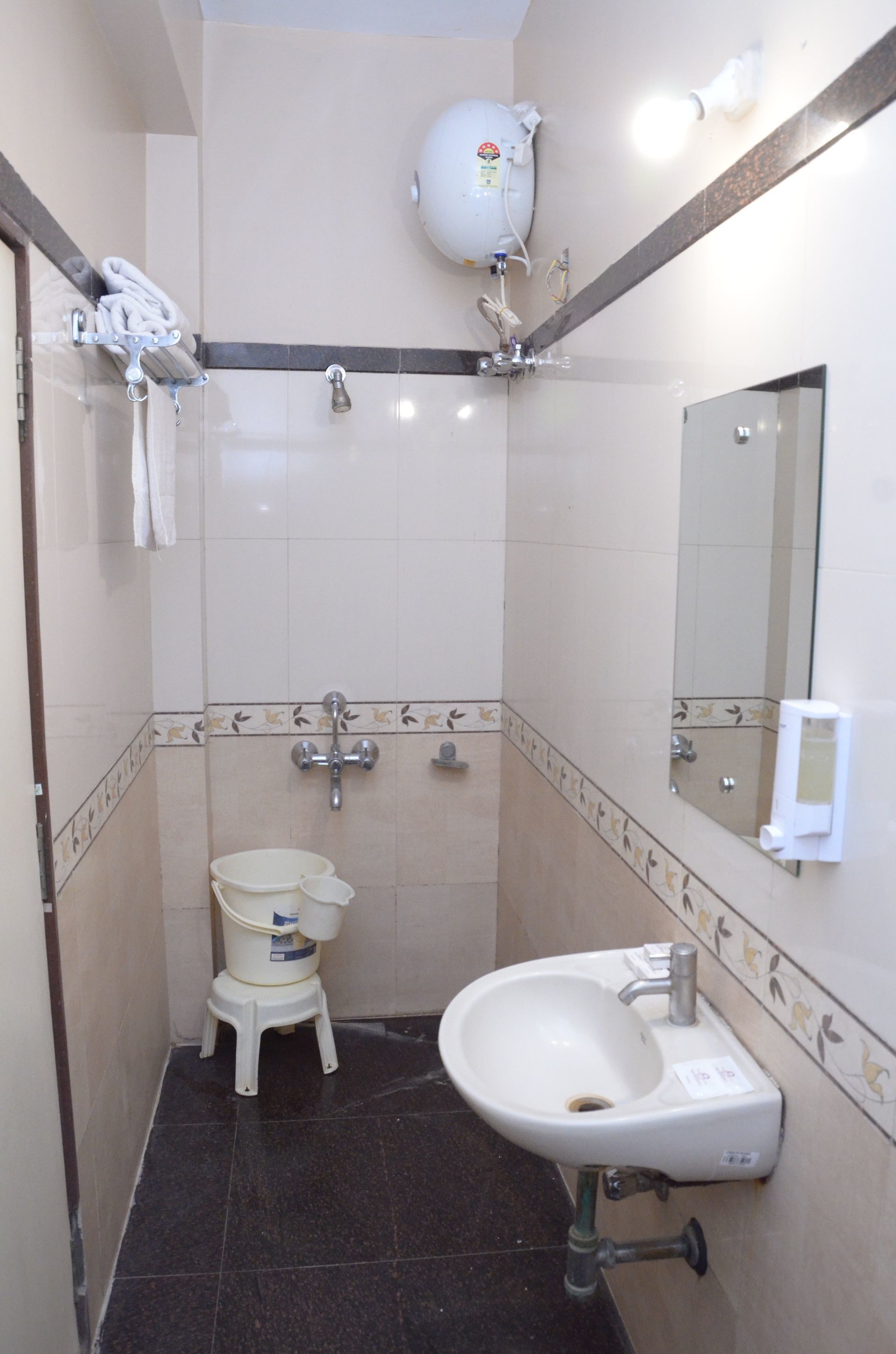 A small bathroom with a white sink, a mirror, a towel rack, and a shower head.