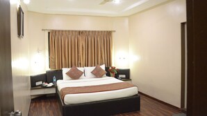 Habitación de hotel con cama, dos mesitas de noche, un ventilador de techo y una ventana con cortinas.
