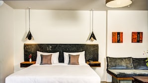 Ein modernes Schlafzimmer mit einem großen Bett, Nachttischen, einer Couch und Kunstwerken an den Wänden.