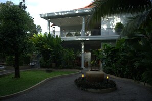 Un hotel con un espacio exterior cubierto, una fuente central y abundante vegetación.