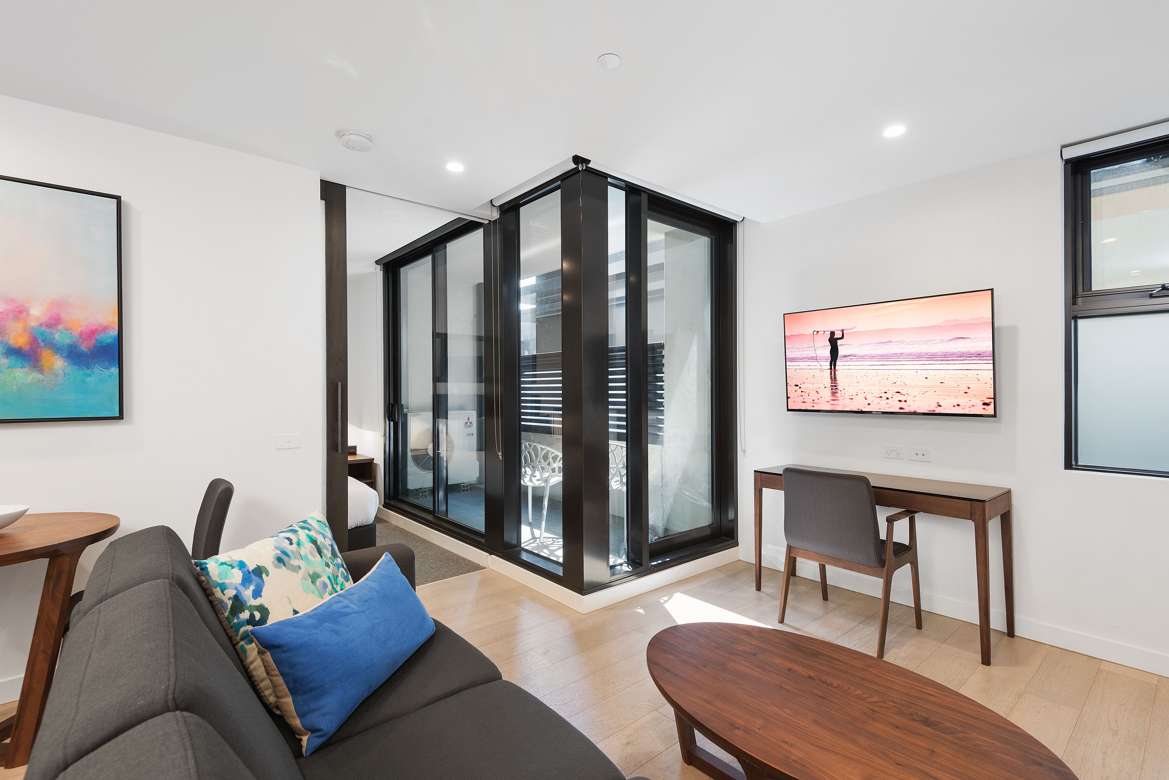 A modern living room with a sofa, a coffee table, and a TV on a wall.