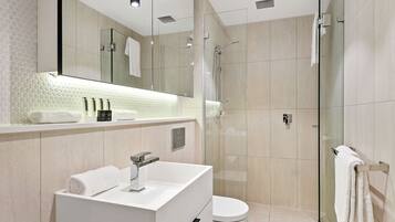 A modern bathroom with a glass-enclosed shower, a white sink, and a large mirror.