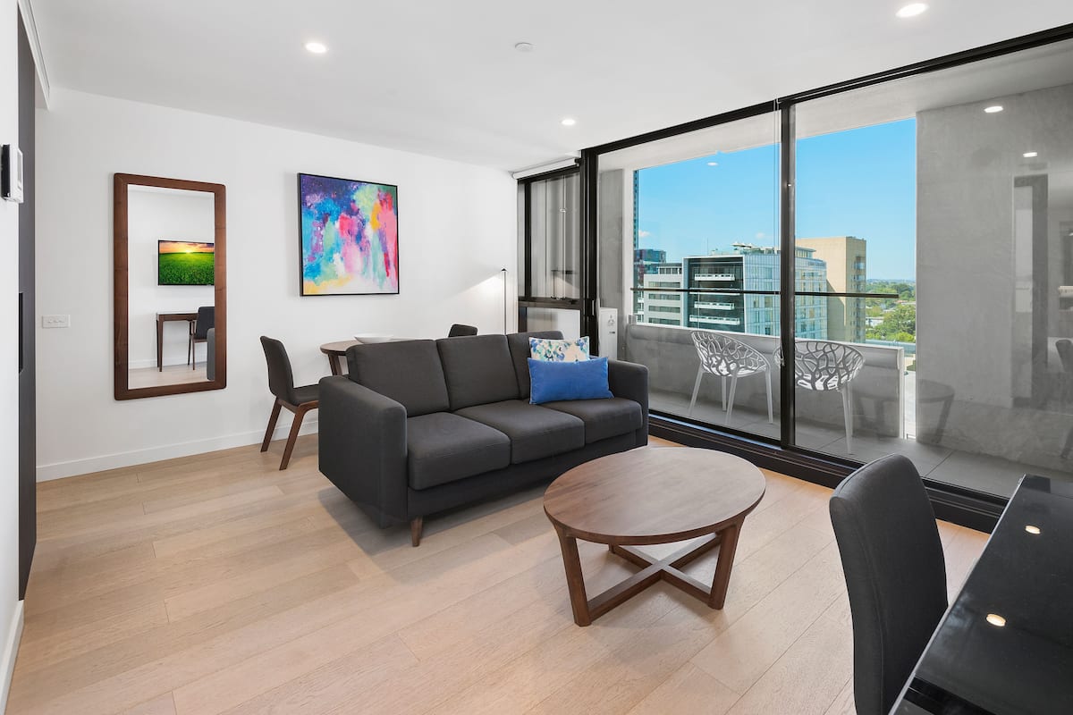A modern living room with a sofa, coffee table, and a balcony with a city view.