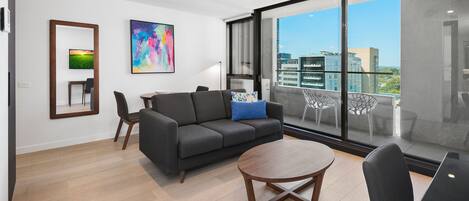 A modern living room with a sofa, coffee table, and a balcony with a city view.
