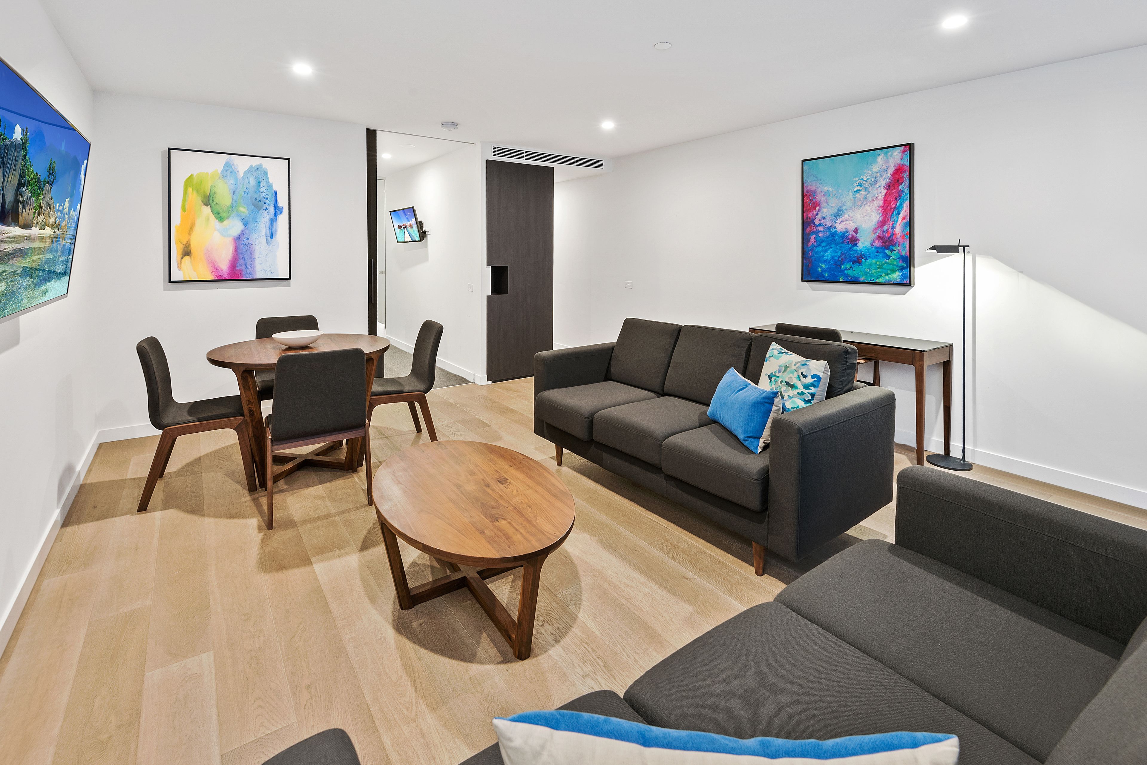 A modern living room with a sofa, a coffee table, and a dining table with chairs.
