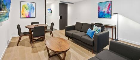 A modern living room with a sofa, a coffee table, and a dining table with chairs.