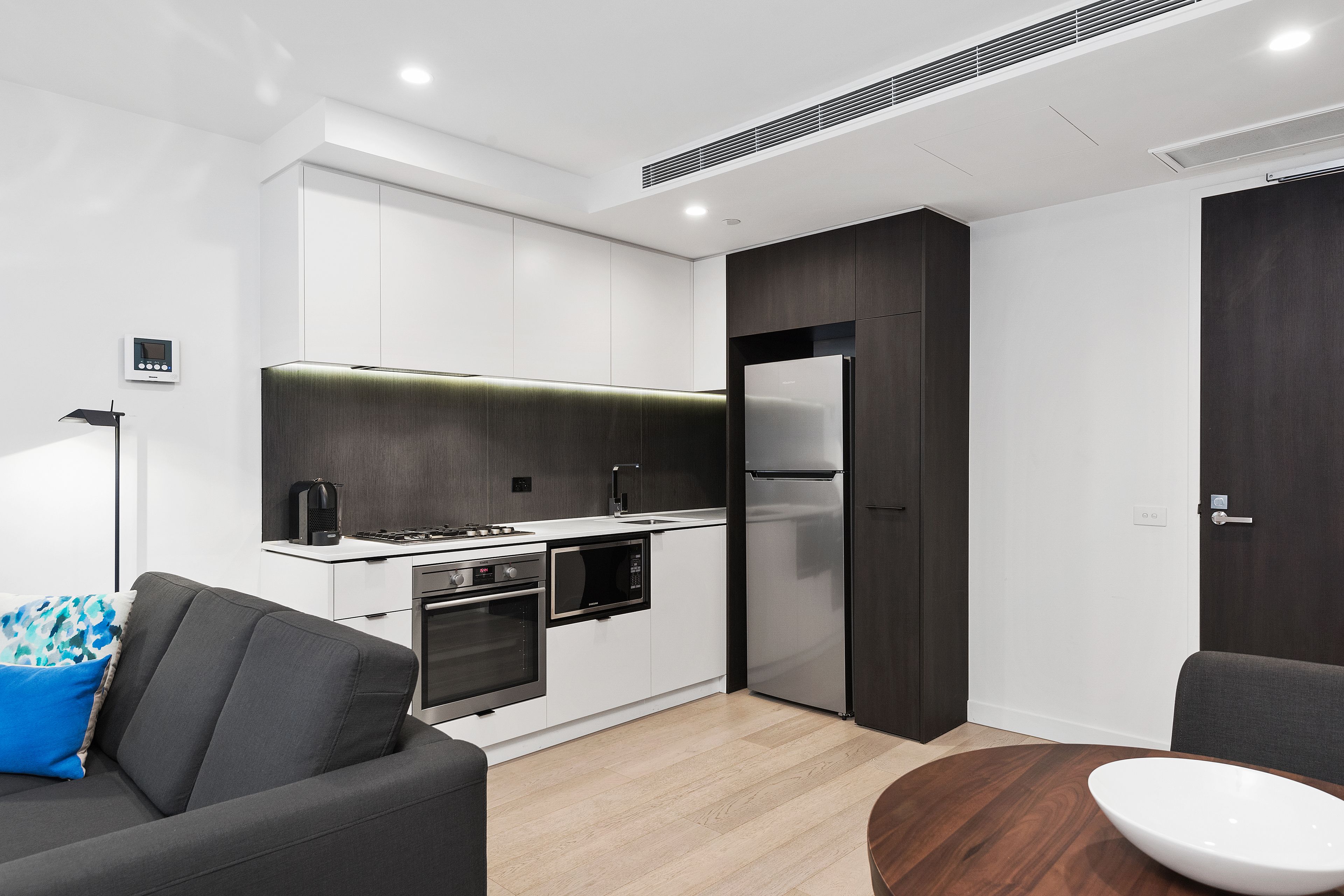 Una cucina moderna con mobili bianchi, forno integrato, microonde e frigorifero in acciaio inossidabile.