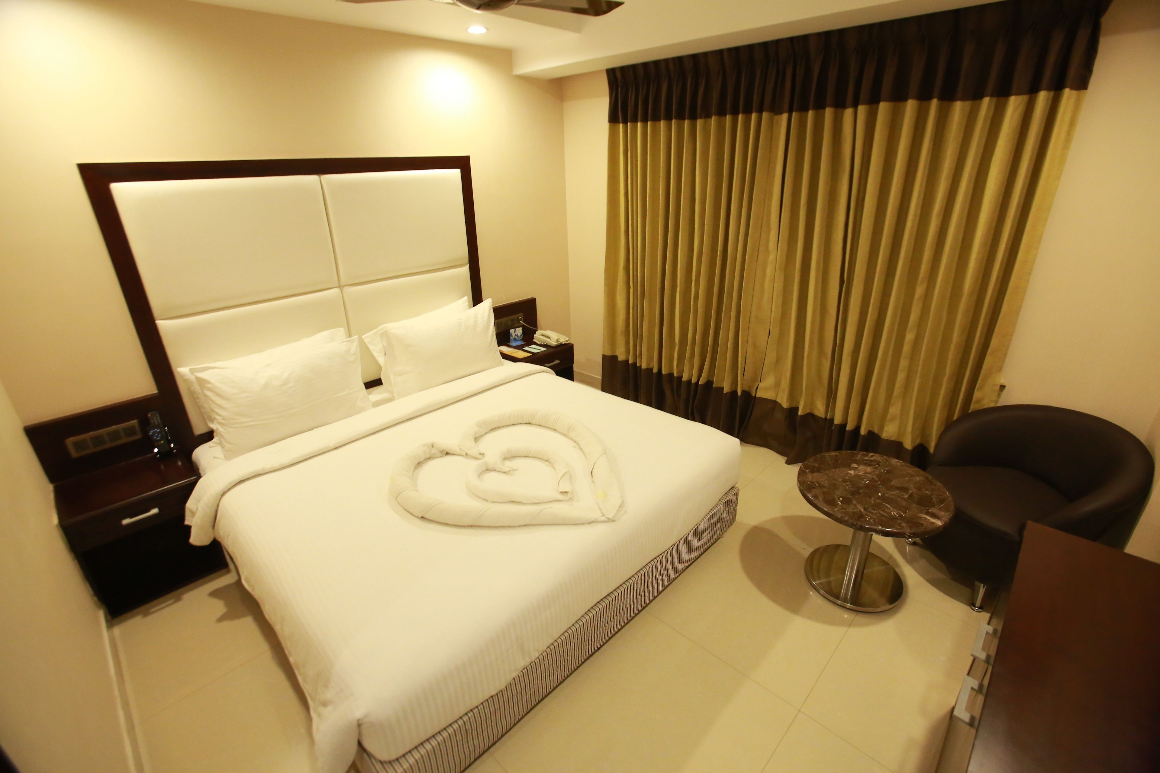 Una habitación de hotel con una cama grande, una mesita de noche, una pequeña mesa redonda y una silla.