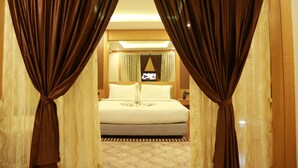 Una habitación de hotel con cama, cortinas y televisor en la pared.
