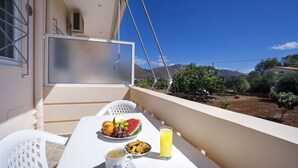 A balcony with a table set for breakfast, including fruits, a drink, and a pastry. - Skamagkas G. Apartments (Chania)
