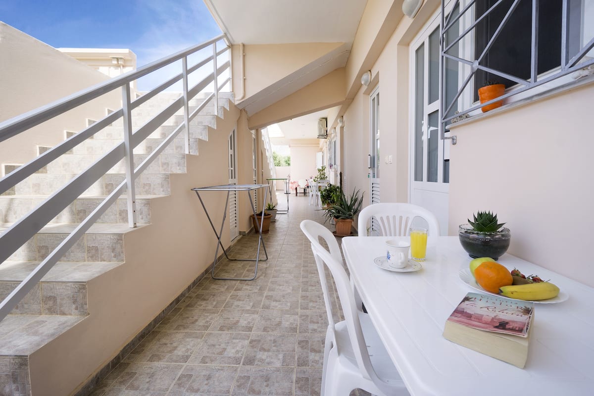 Un balcon avec une table préparée pour le petit-déjeuner, un livre et une plante en pot.