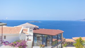 A coastal building with a red-tiled roof, large glass windows, and a view of the sea. - Peace Hotel (Kas)