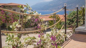 A rope barrier with a view of a coastal area, including a building with a red-tiled roof and a mountainous backdrop. - Peace Hotel (Kas)