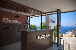 A reception desk with a 'Peace' sign, a view of the sea, and a brick wall. - Peace Hotel (Kas)