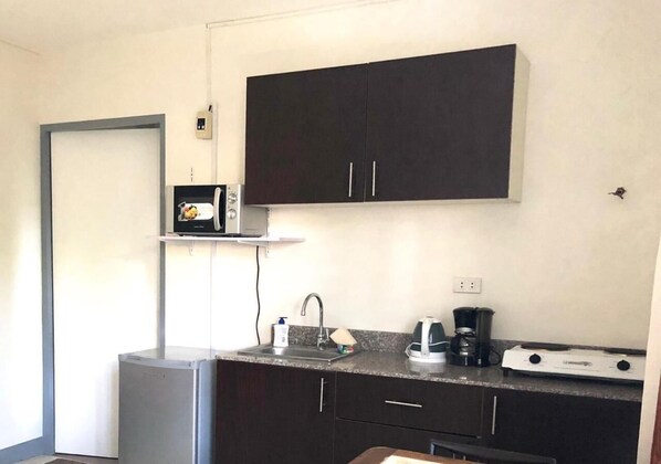 Cocina compacta equipada con microondas, cafetera y un refrigerador pequeño.