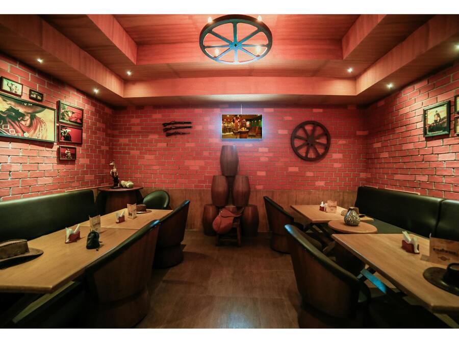 A restaurant with brick walls, wooden tables, and green booths.