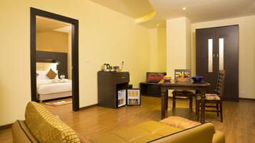 Une chambre d’hôtel comprenant un lit, un canapé, une table à manger avec des chaises, un petit coin cuisine et une porte donnant sur une autre pièce.
