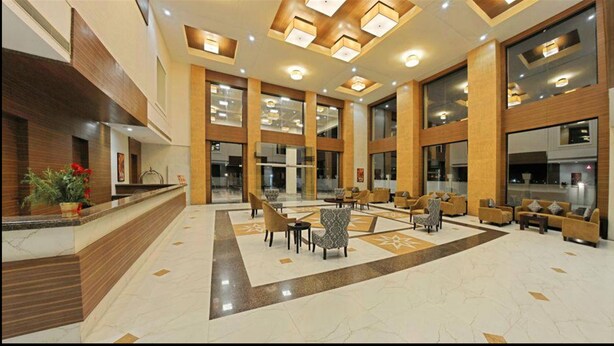 A spacious lobby with a reception desk, multiple seating areas, and large windows allowing natural light. - Poppys Hotel (Madurai)