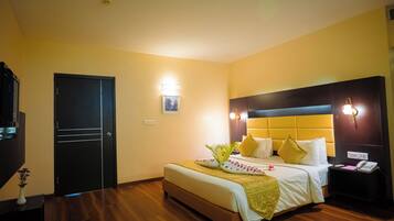 Una habitación de hotel con cama, mesita de noche, lámpara y una puerta.