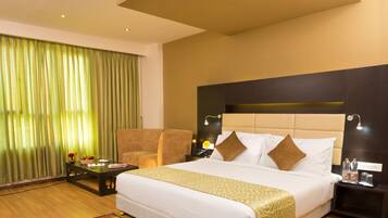 A hotel room with a large bed, a chair, a nightstand, and a desk.
