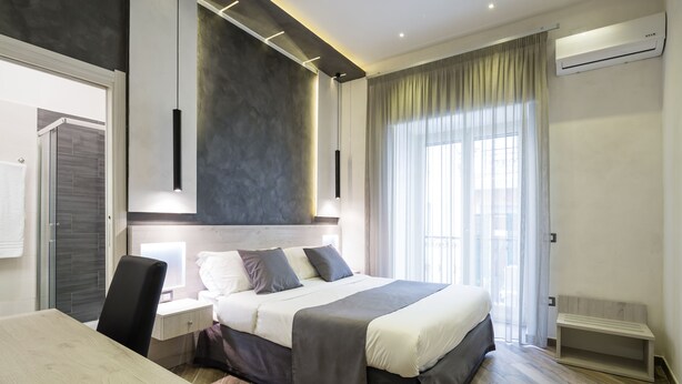 A modern bedroom with a large bed, bedside tables, a desk, and a chair. - Hotel Bella Napoli (Naples)