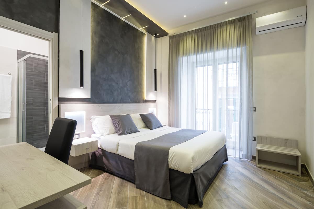A modern bedroom with a large bed, bedside tables, a desk, and a chair.