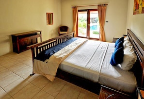 Un dormitorio con cama, una silla, un escritorio y un ventanal con cortinas.