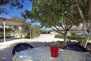 Un patio al aire libre con una mesa cubierta, sillas y una planta en maceta.