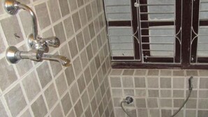 A small bathroom with a toilet, a shower, and a sink. - Hotel Peace N Park (Kathmandu)