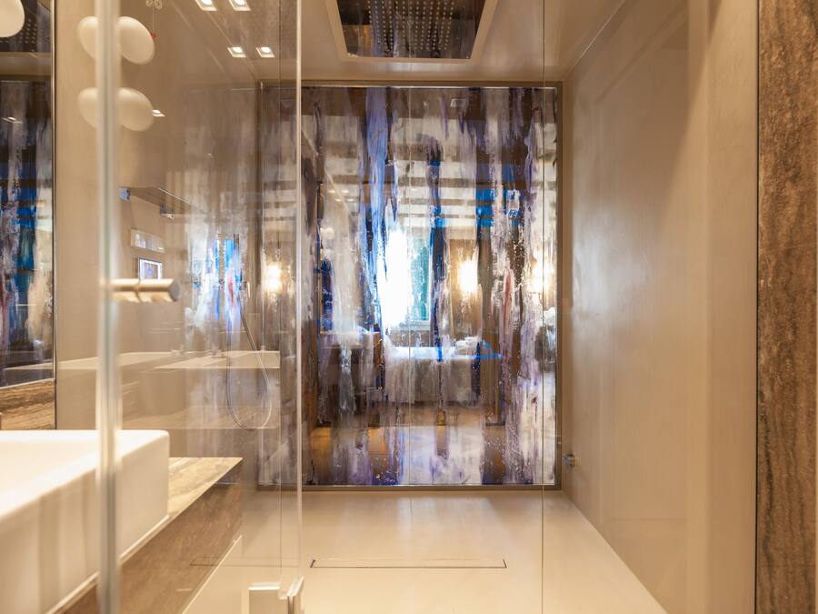 A modern bathroom with a glass partition, a white sink, and a marble countertop.