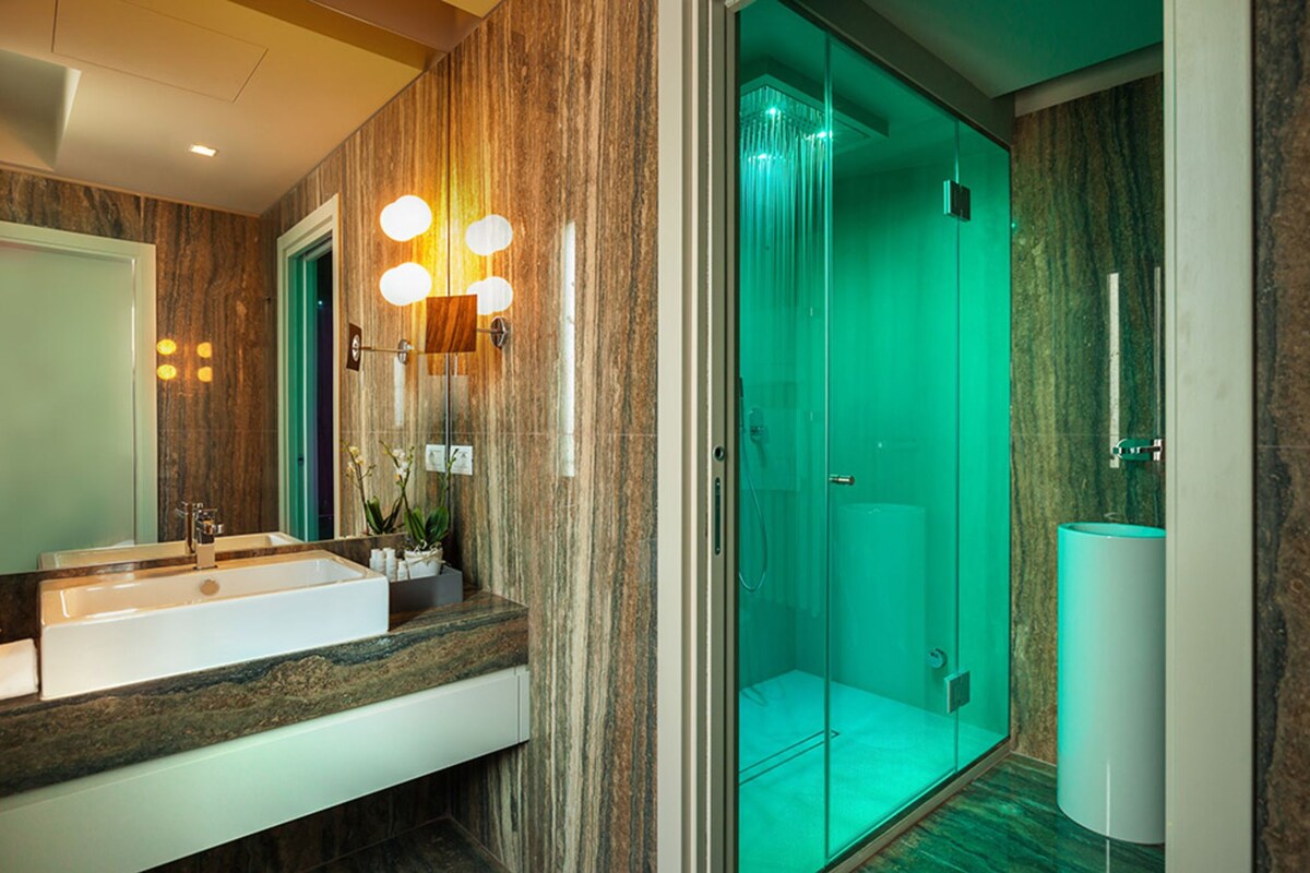 A modern bathroom with a large sink, mirror, and a glass-enclosed shower.