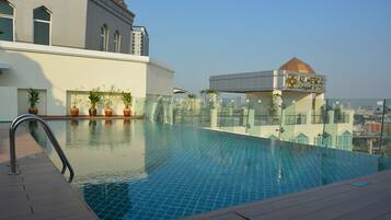A rooftop swimming pool with a clear view of the cityscape in the background.