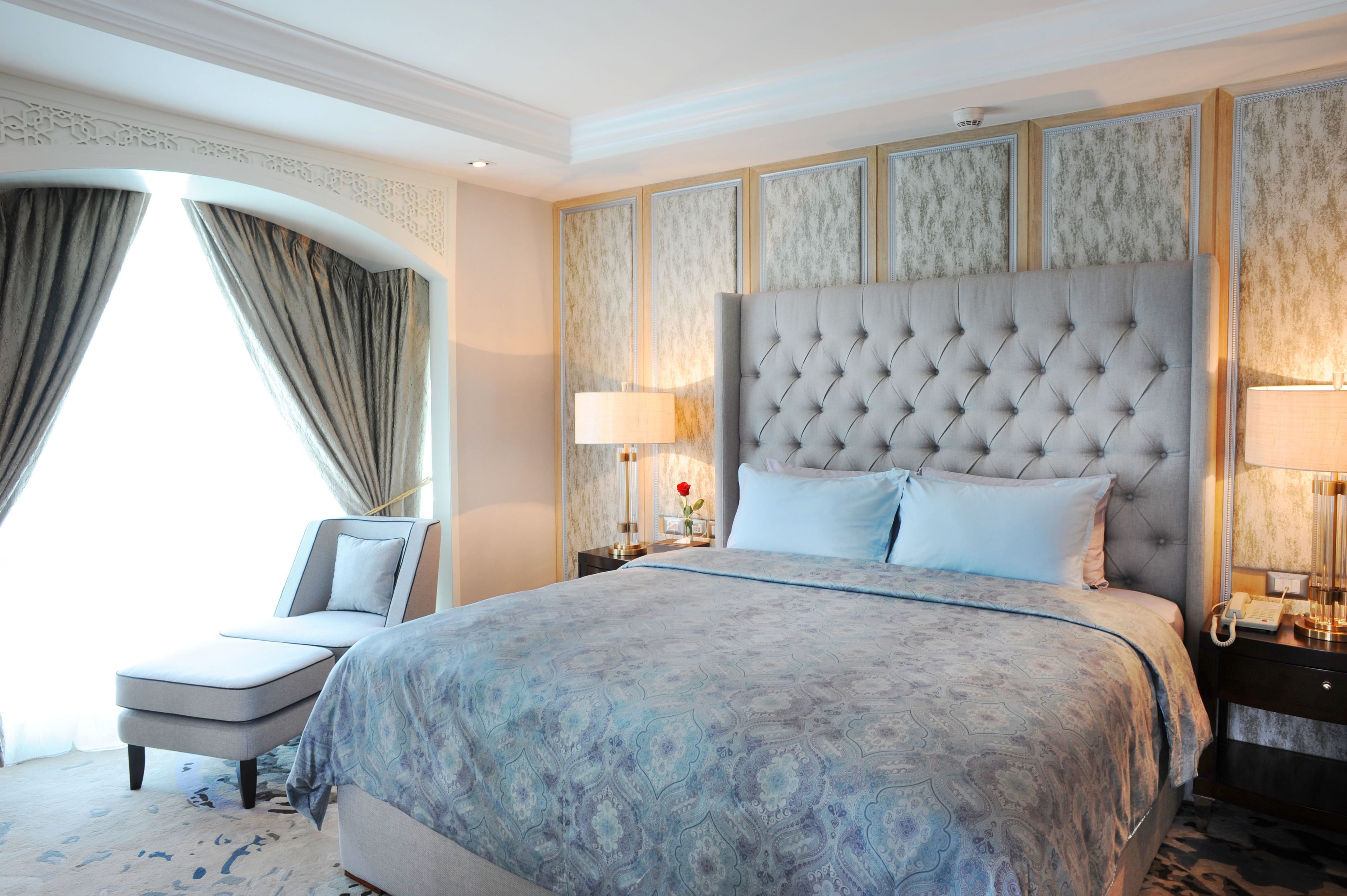 A hotel room with a large bed, a sitting area, and a view of the outdoors.