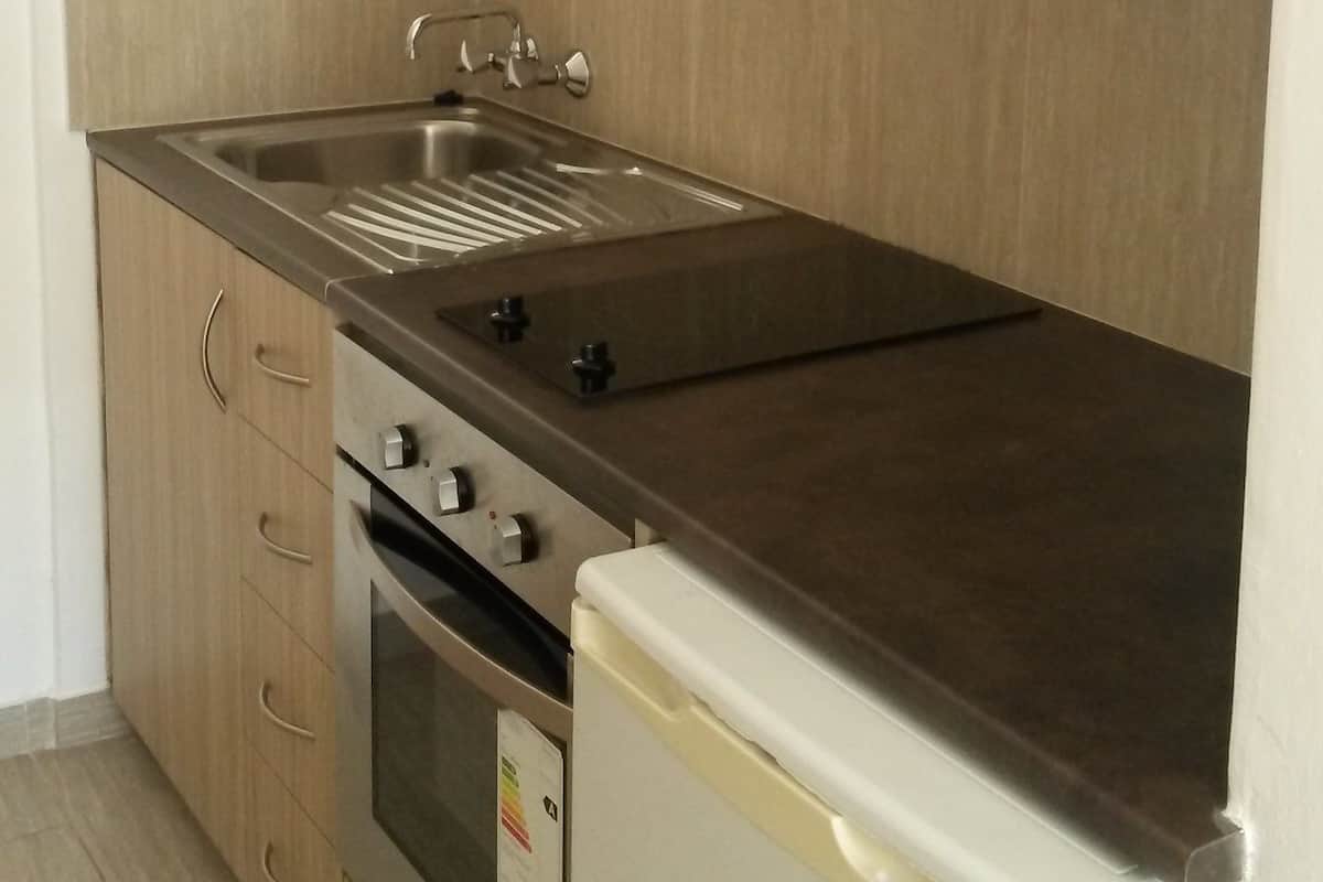 A kitchen with wooden cabinets, a stainless steel sink, a built-in oven, and a white refrigerator.