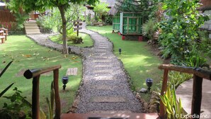 Un sendero de jardín que lleva a una estructura verde, rodeada de abundante vegetación y una escalera de piedra.