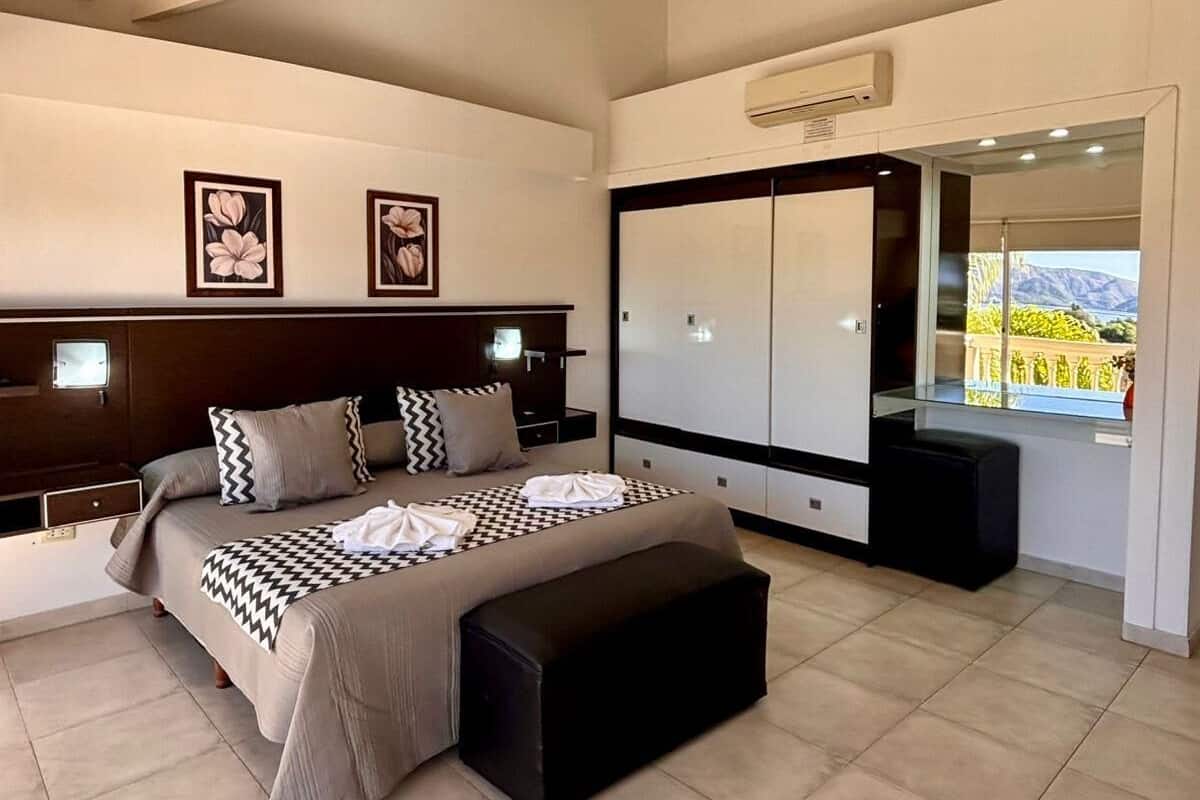Een moderne slaapkamer met een bed, een kledingkast en een groot raam met uitzicht.