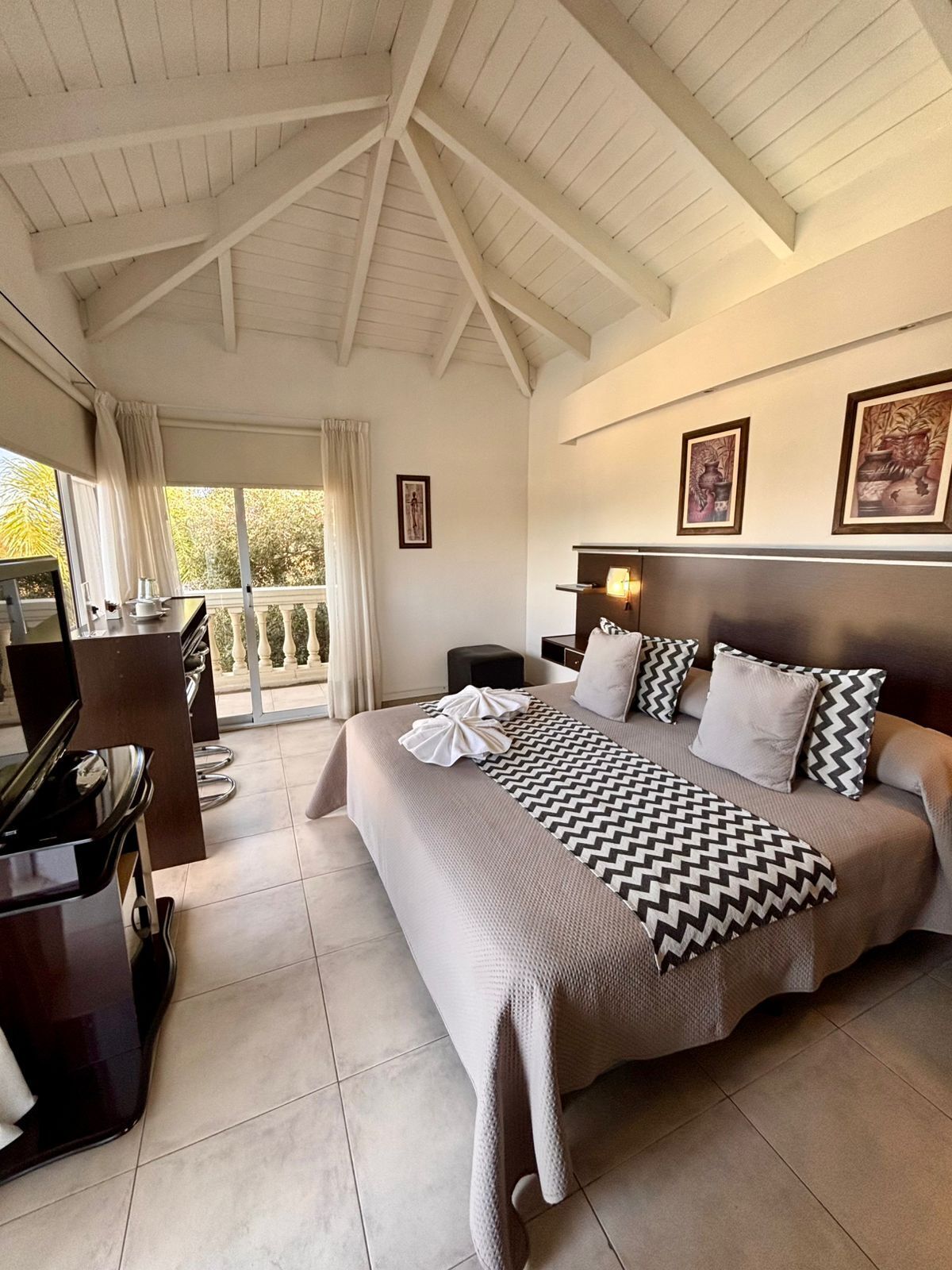 A spacious bedroom with a large bed, a piano, and a balcony with curtains.