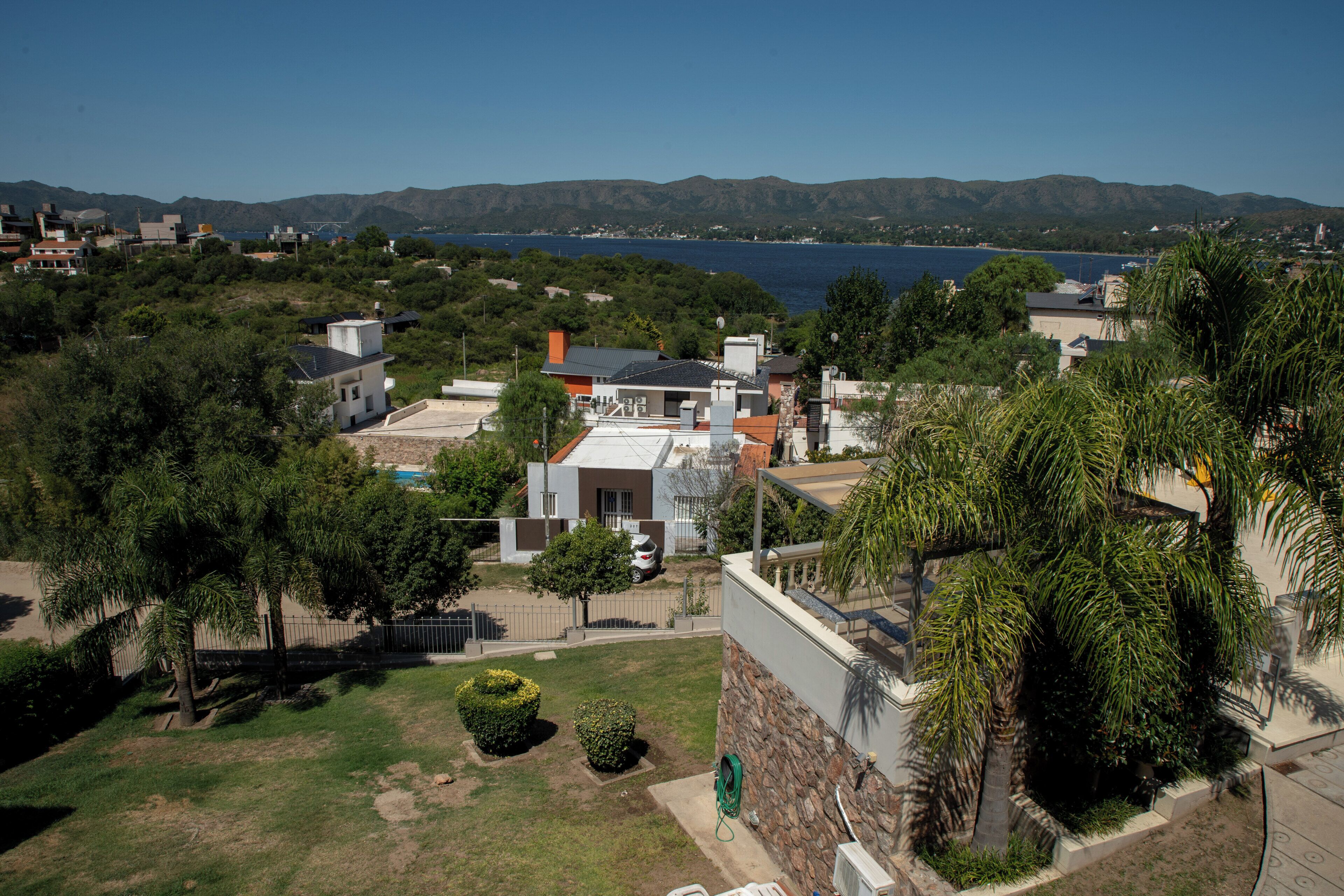 A residential area with houses, a clear blue sky, and a body of water in the background.
