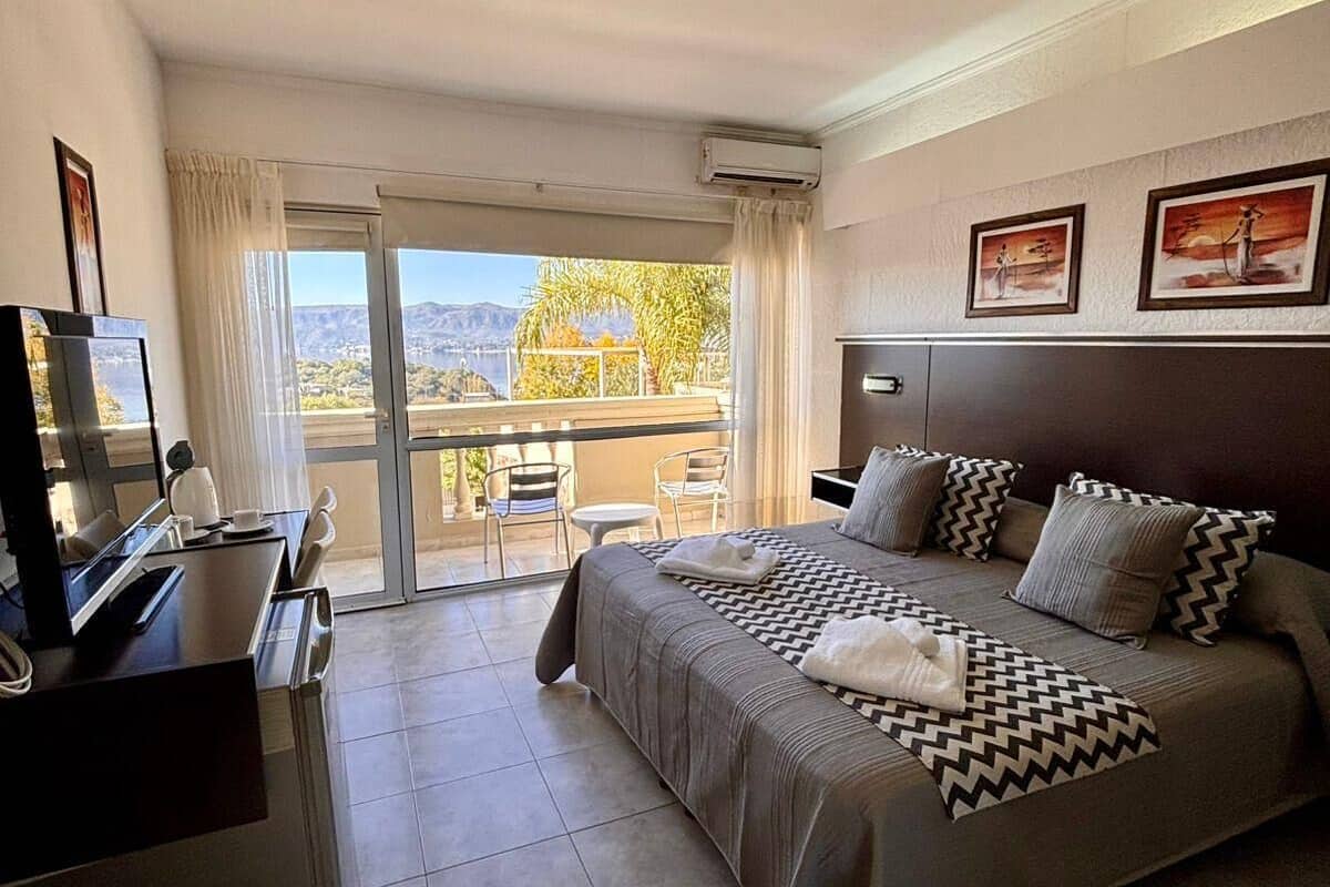 Een hotelkamer met een bed, een bureau, een stoel en een balkon met uitzicht.