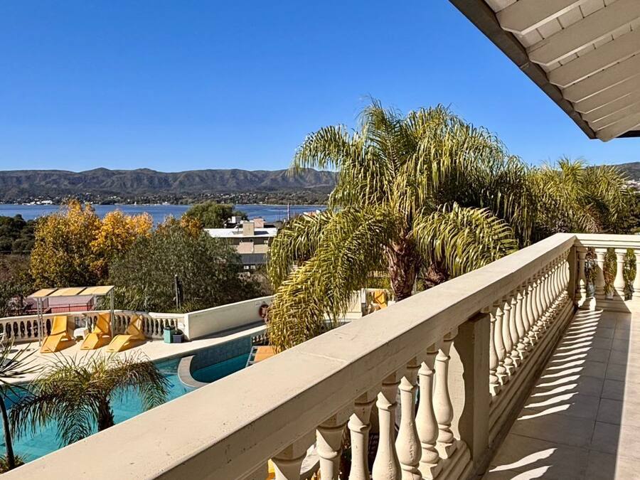 A balcony with a pool, a view of a lake, and distant mountains.