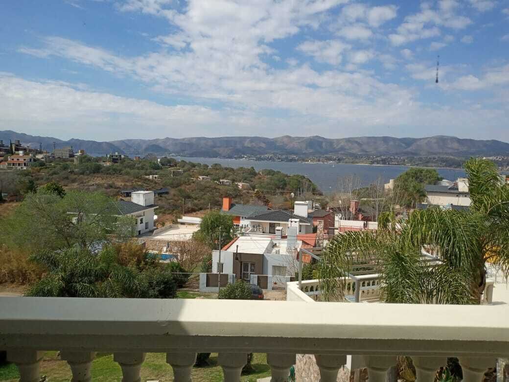 A residential area with houses, a body of water, and mountains in the background.