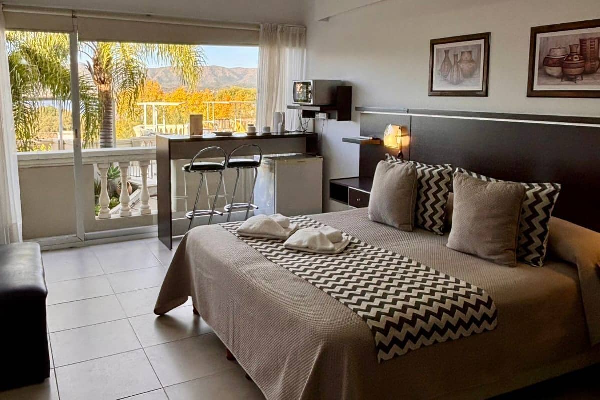 Hotelkamer met een bed, een bureau, een stoel, een televisie en een balkon met uitzicht.