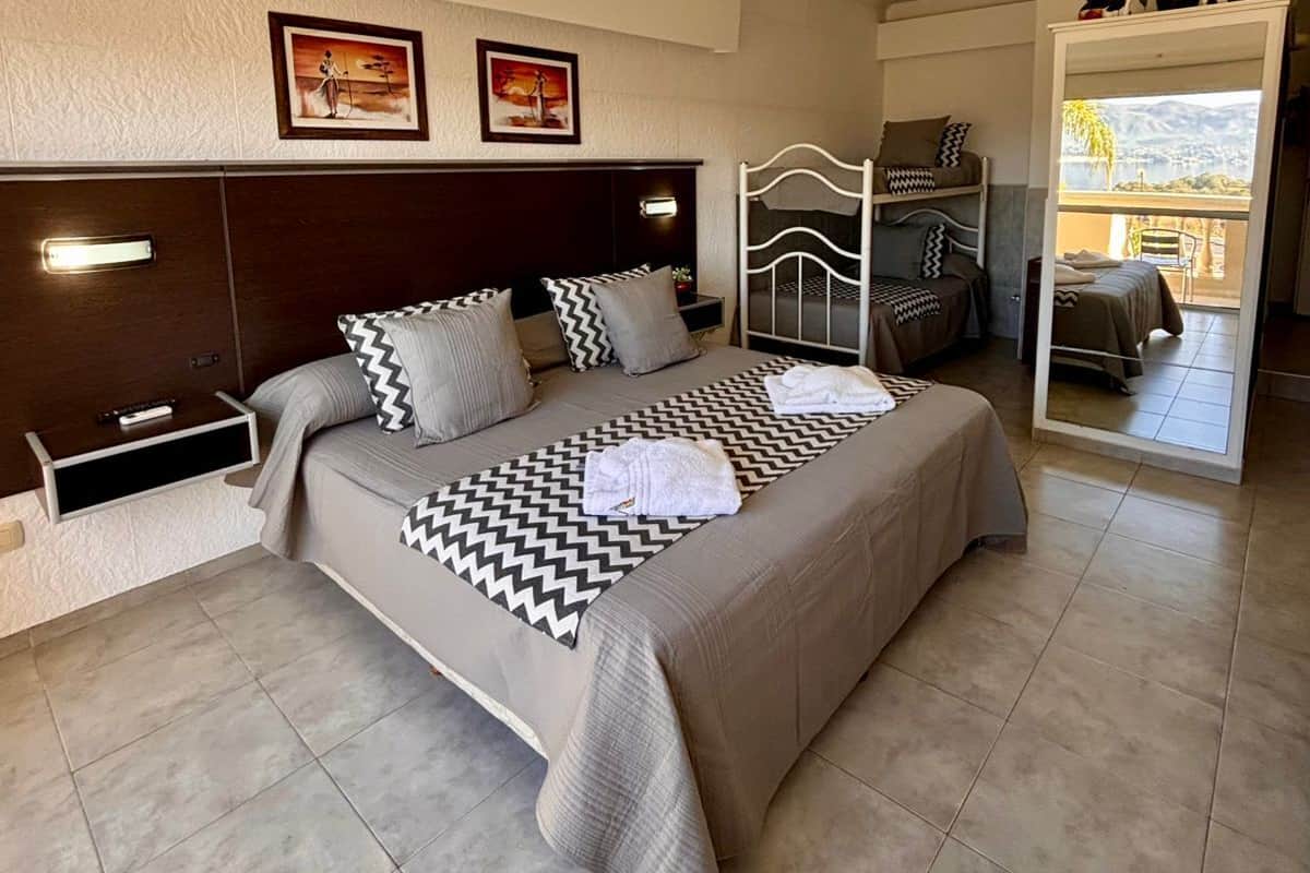 Een hotelkamer met een bed, nachtkastjes, een spiegel en kunst aan de muur.