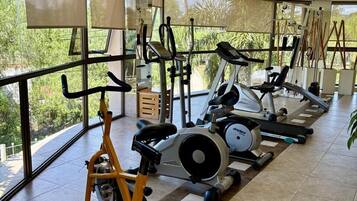 A gym with exercise equipment, large windows, and a tiled floor.