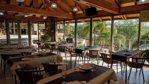 Ein Restaurant mit gedeckten Tischen, großen Fenstern mit Blick ins Freie und einer Holzzieldecke.
