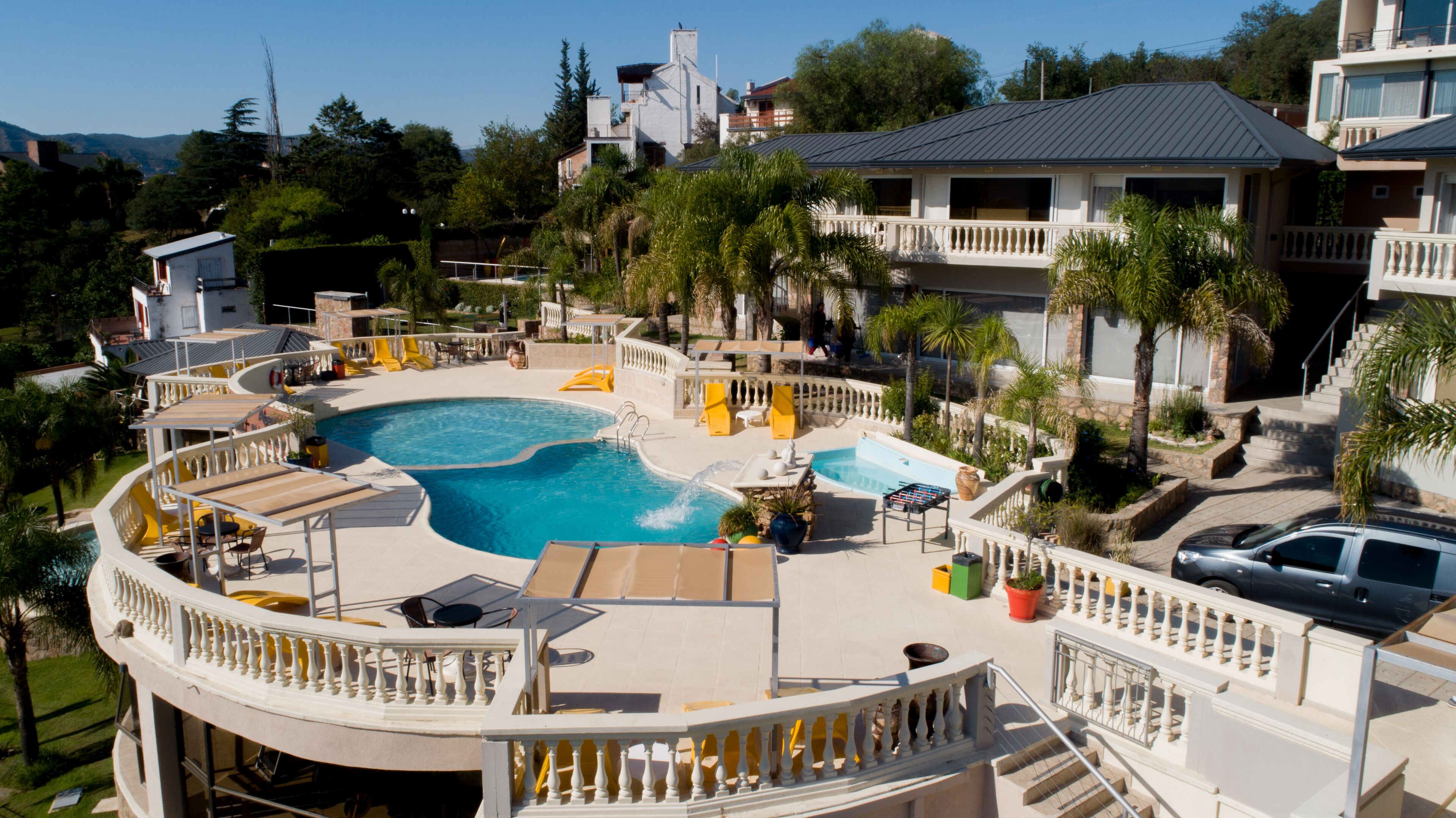 A resort with a large pool, sun loungers, and a view of surrounding buildings.