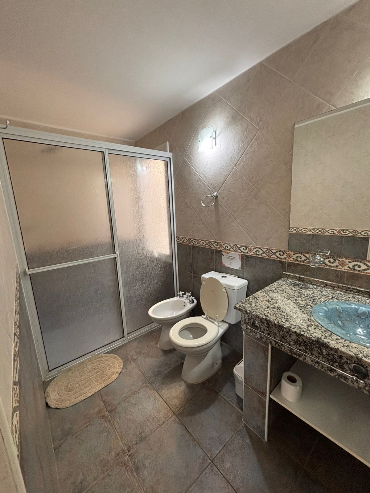 A bathroom with two toilets, a bidet, a shower, and a marble sink.