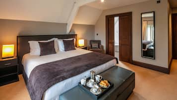 A neatly arranged bedroom with a large bed, bedside tables, a chair, and a tray of breakfast items.